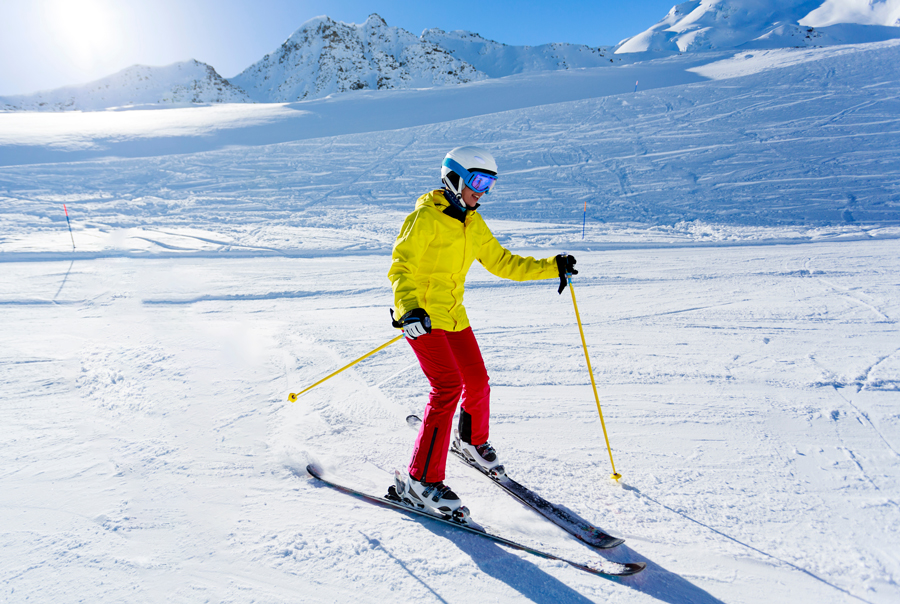Woman in yellow jacket snowplough skiing